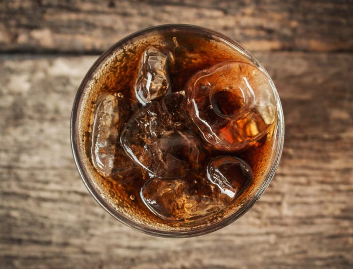Cola in glass with ice from top view on table.