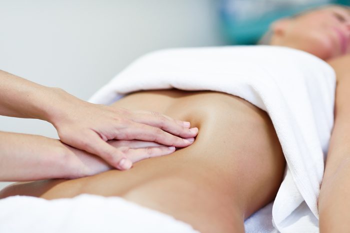 Therapist applying pressure on a woman's abdomen.