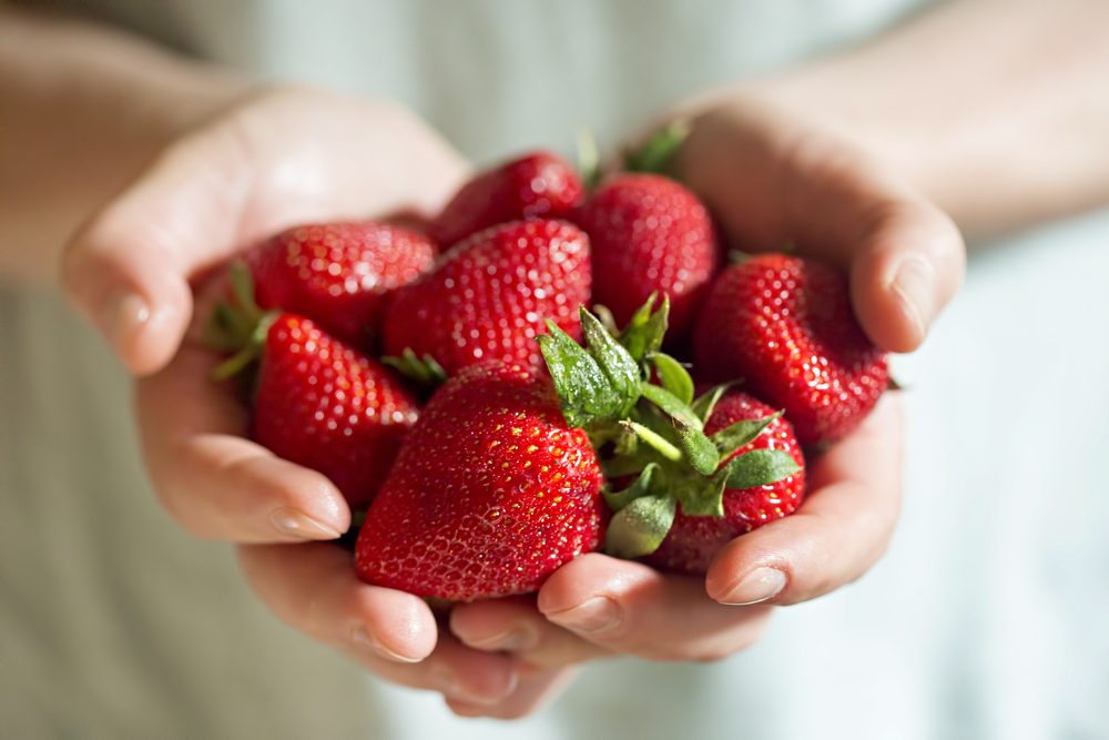hands holding fresh strawberries