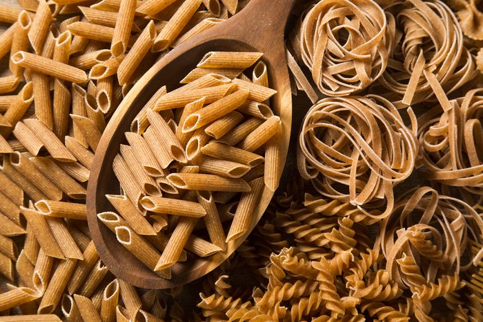 Wholemeal Fusilli into a spoon. Integral Pasta over a wooden table
