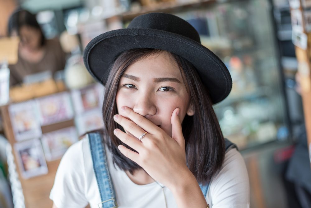 girl covers her mouth with her hands after passing gas