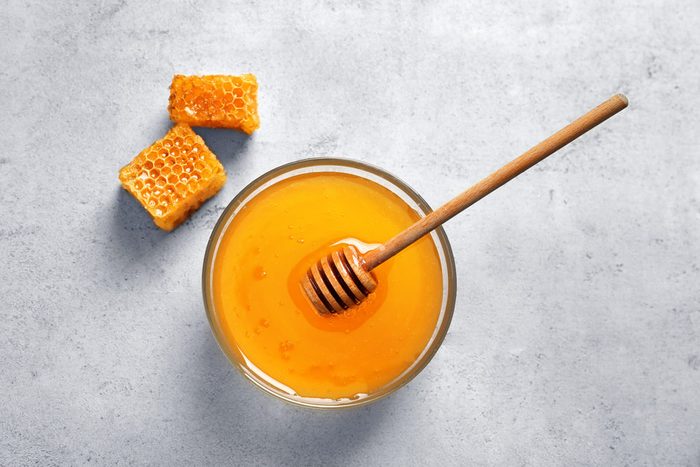 Glass bowl with delicious honey and dipper on table