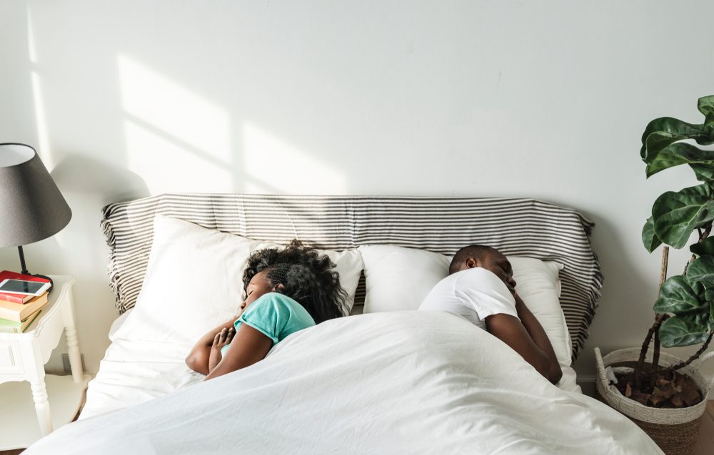 couple sleeping back to back in bed