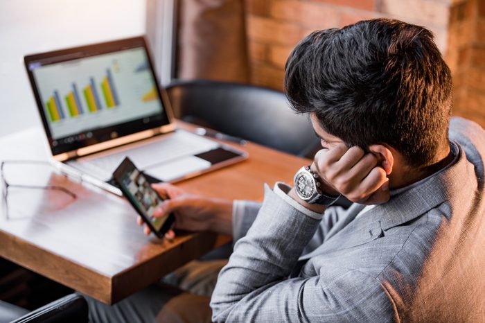 man procrastinating work by looking at smartphone