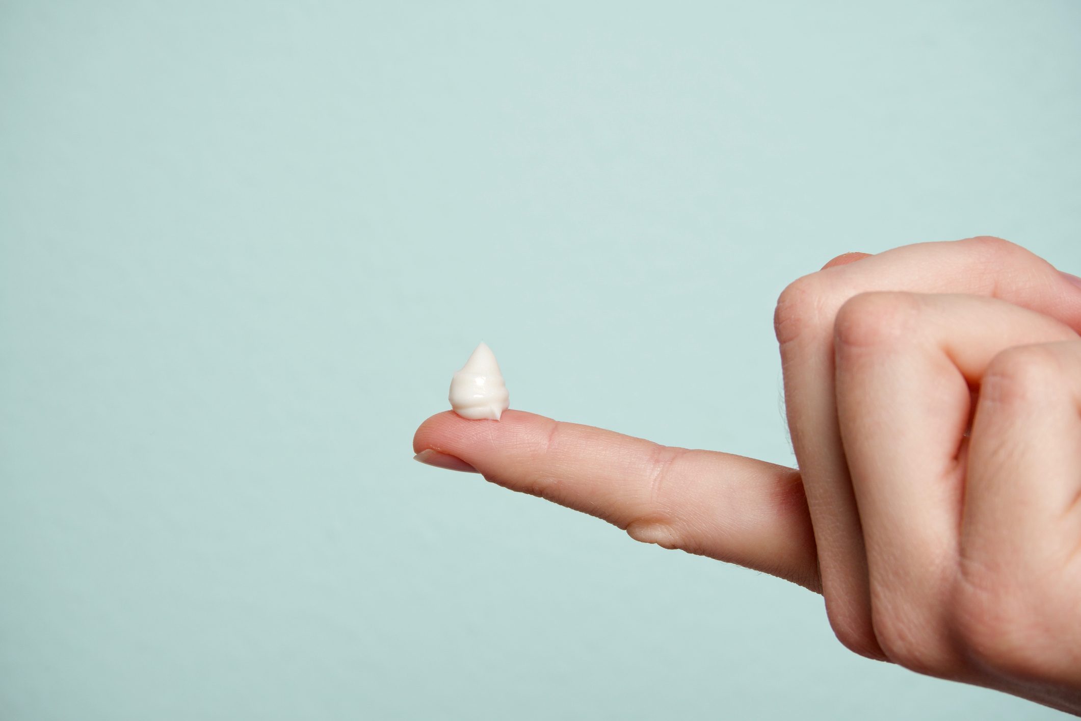 cropped hand with lotion on finger tip