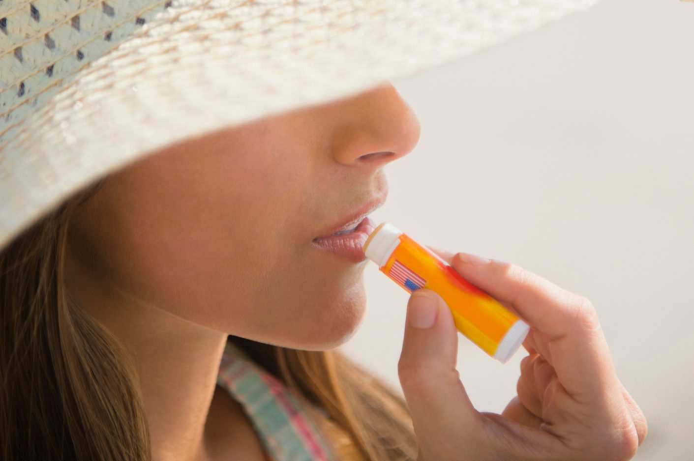 woman applying lip balm sunscreen at the beach