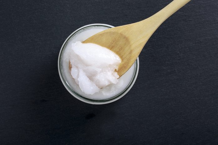Coconut oil in a glass jar on a black. Top view. Copy space.