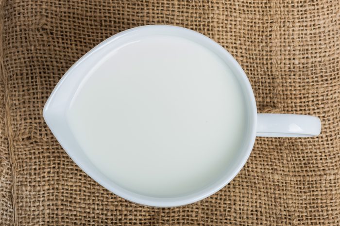 Cow milk and ceramic jug on wooden table