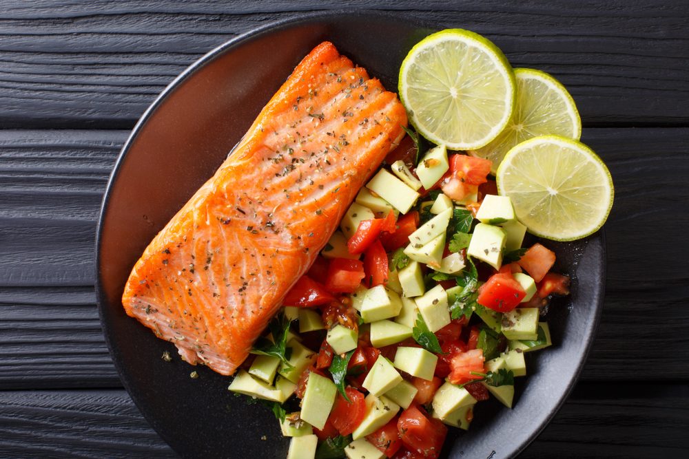 spicy baked salmon steak and fresh vegetable salad close-up on a plate. horizontal top view from above