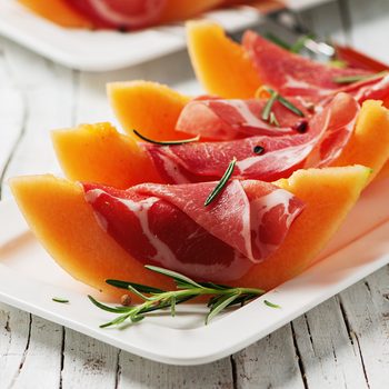 Concept of italian food with melon and prosciutto, selective focus