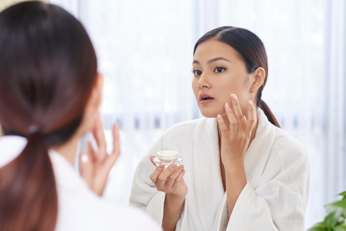 woman applying cream to her face