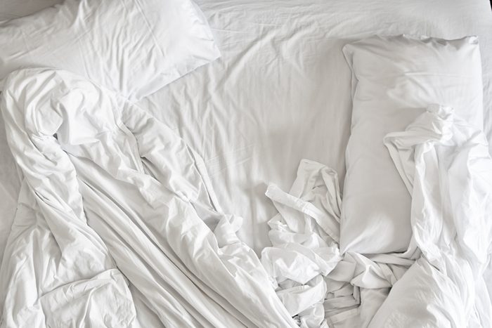 Top view of unmade bedding sheets and pillow