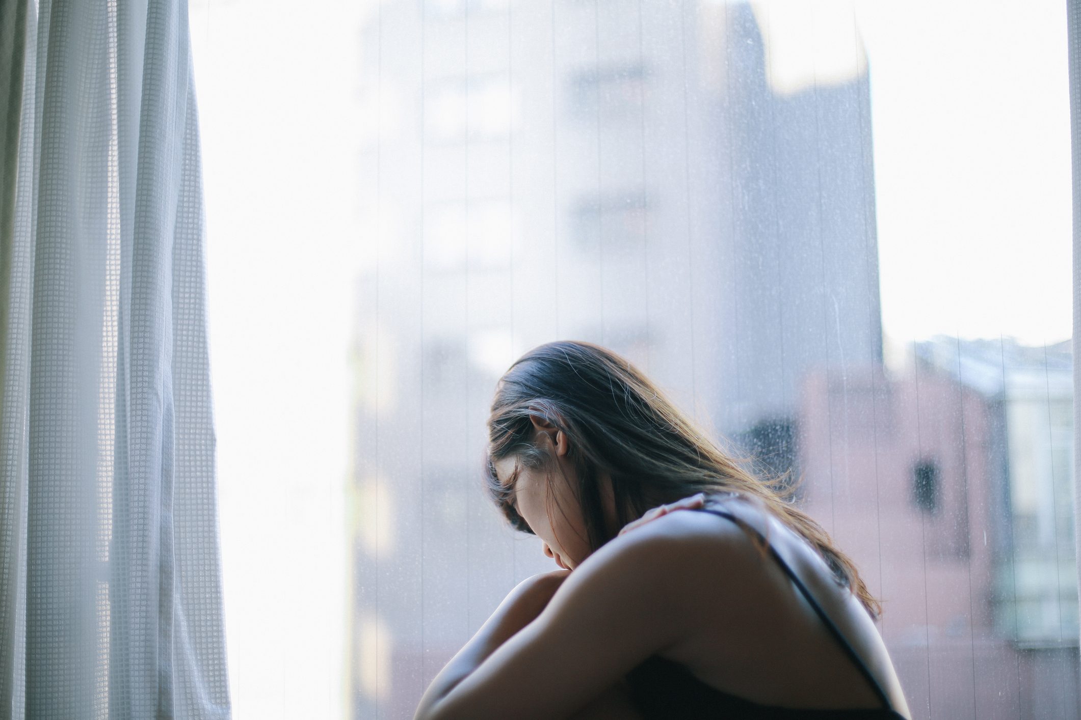 upset woman sitting near window