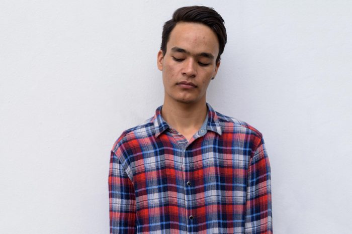 Young man with eyes closed looks sullen.