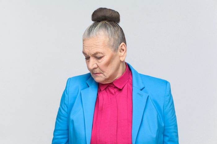 Gray haired woman in bright clothing looking down.