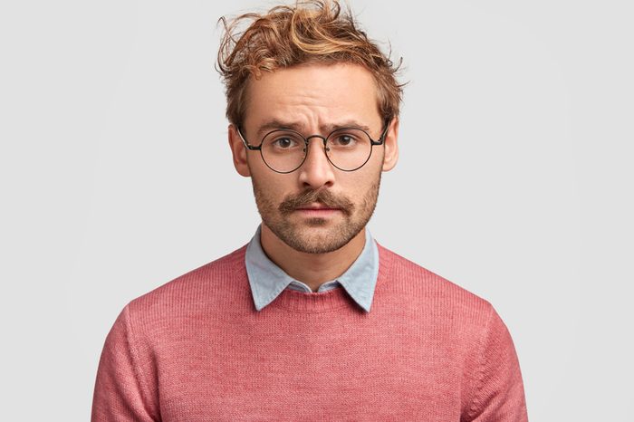 Serious young man furrows his brow, looks directly ahead.