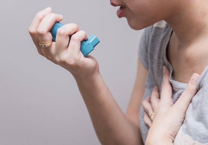 Asian woman using a pressurized cartridge inhaler extended pharynx, Bronchodilator