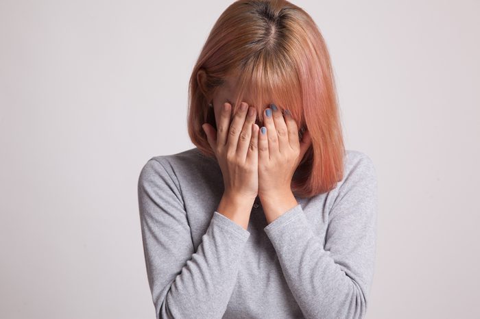 Sad young woman with hands covering her face.
