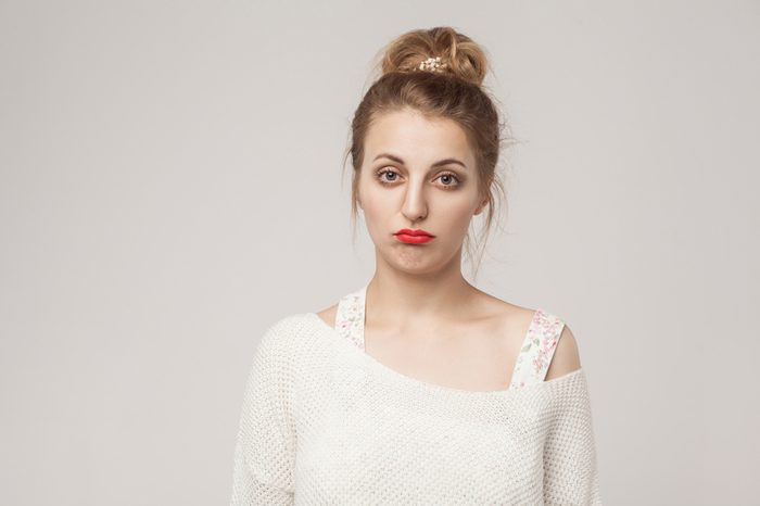 Young lady puffs her lips in sad expression.