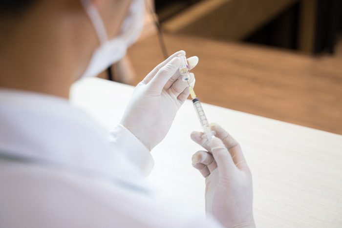 Close up Doctor is injecting patient vaccine in test tube with syringe and stethoscope in lab room . Laboratory environment and medical concept .insulin or vaccination. Hospital office room.