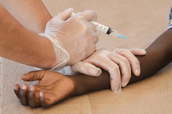 Close-Up of African boy getting a vaccination needle from a volu