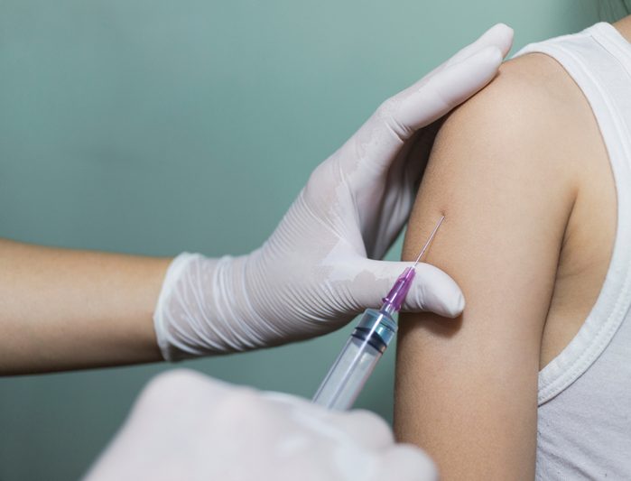 Close up The Doctor inject vaccine to asian girl in the clinic.