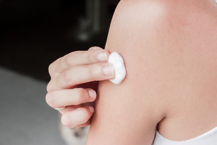 Asian woman is taking vaccine shot on her shoulder.