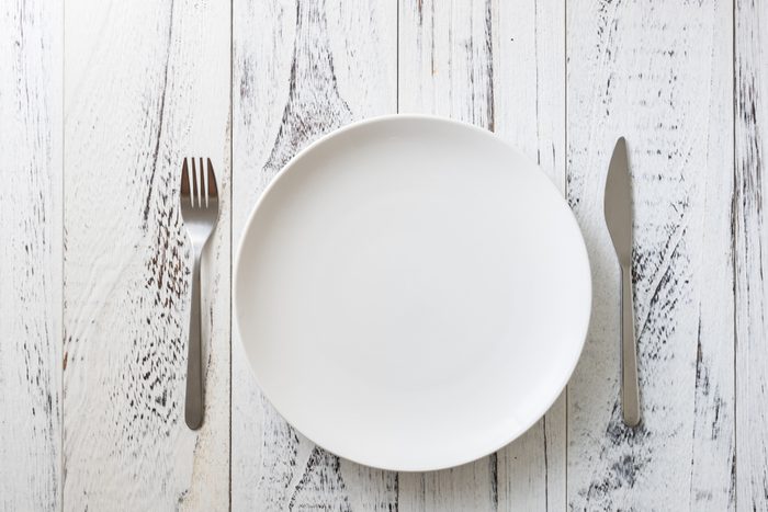 Round Plate with utensils on white wooden table background