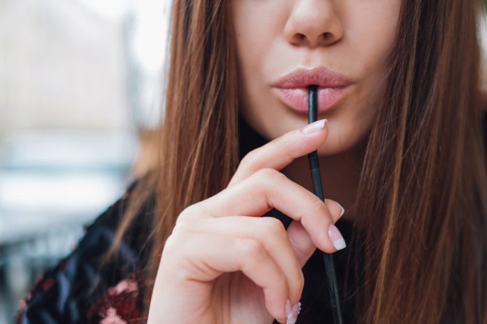 Woman with sexy lips drinking through a straw