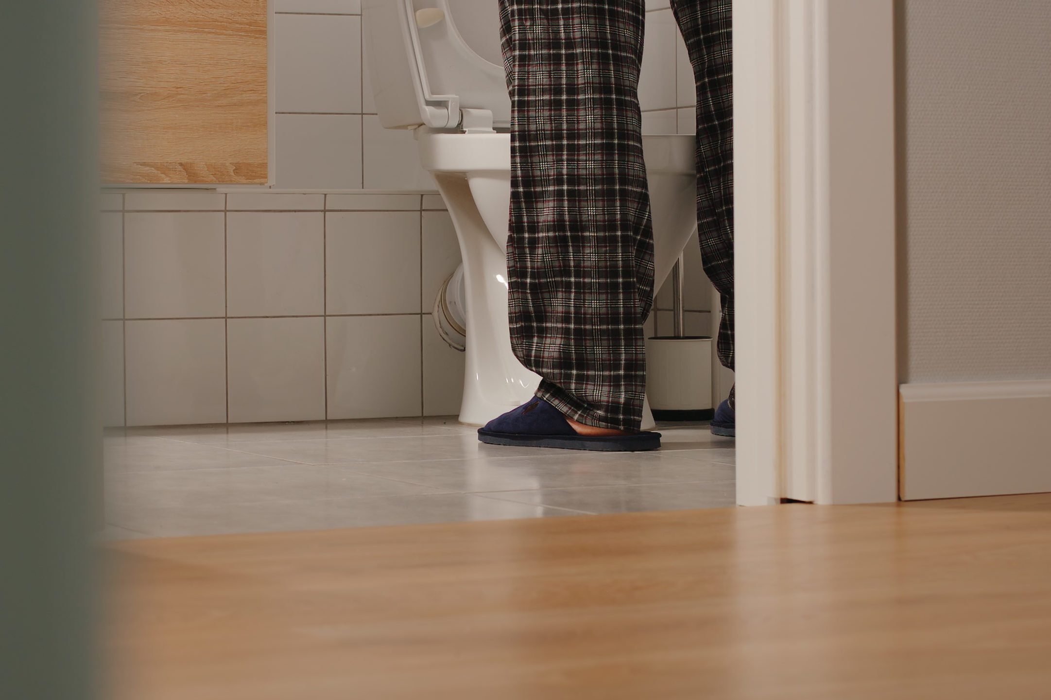 cropped shot of man using the toilet at night