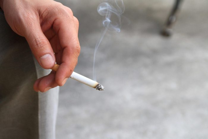 hand holding lit cigarette