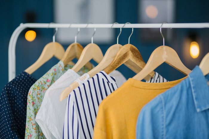 Clothes hang on wooden coat hangers on a clothing rack.