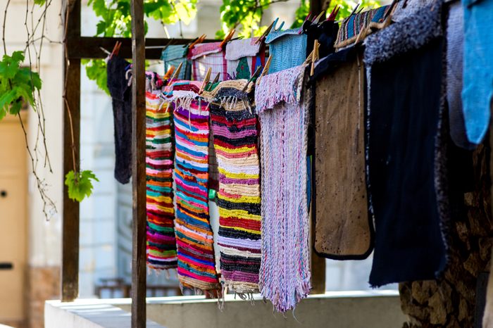 Colorful rugs and mats hanging on a clothing line near the house