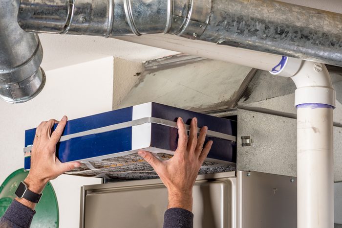 Person changing their home furnace air filter replacement