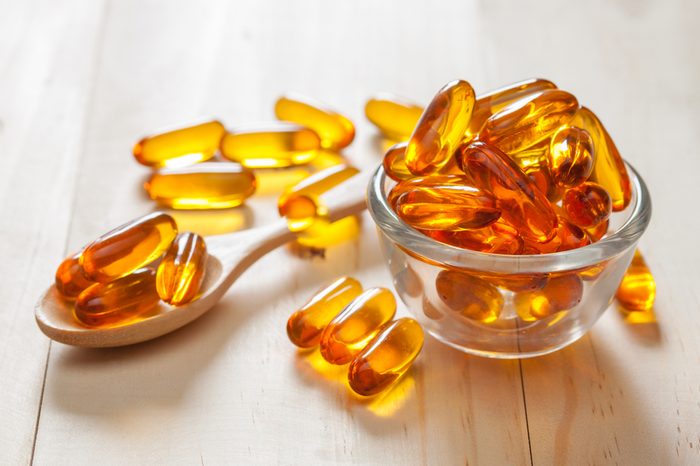 Fish oil capsules on wooden background and texture, vitamin D supplement, selective focus
