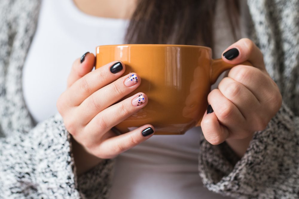 A young pregnant woman holding a cup, close-up
