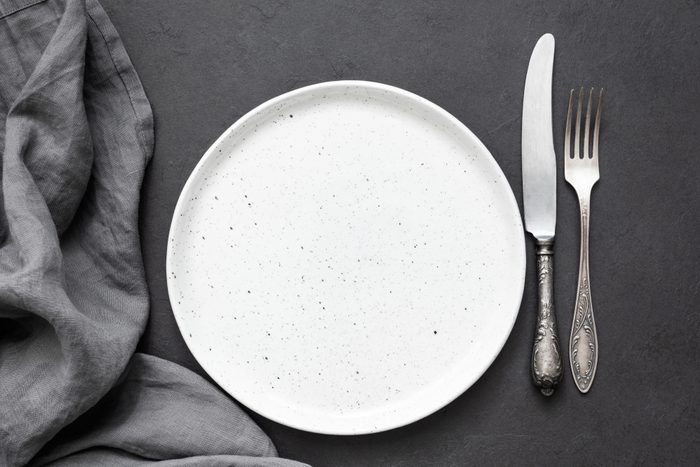 Vintage cutlery or silverware, empty plate and kitchen textile napkin. Top view, copy space for text