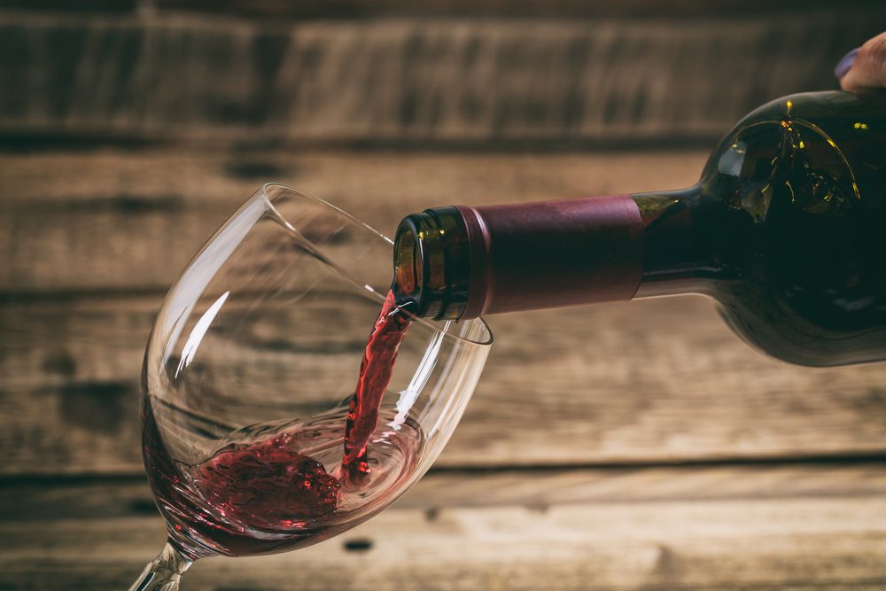 Pouring red wine in a glass on a wooden table