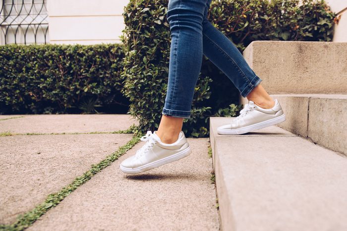 Legs of pretty woman in the sneakers walking downstairs. Horizontal outdoors shot.