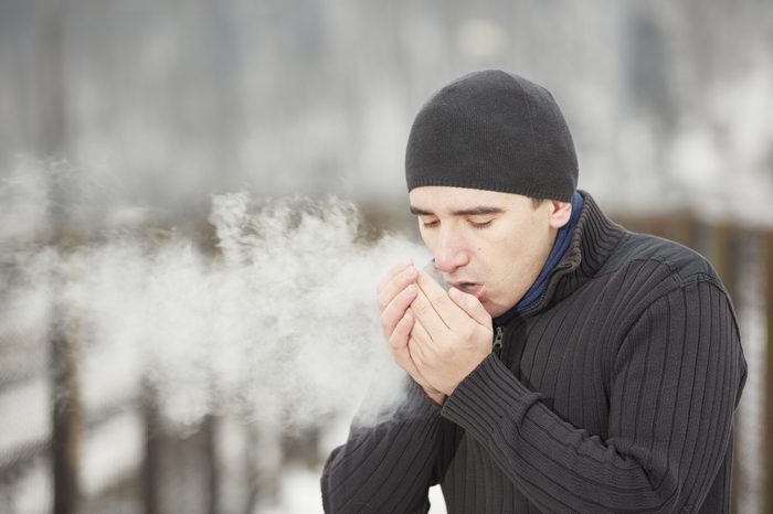 Young man in winter landscape and warmed the hands of breath