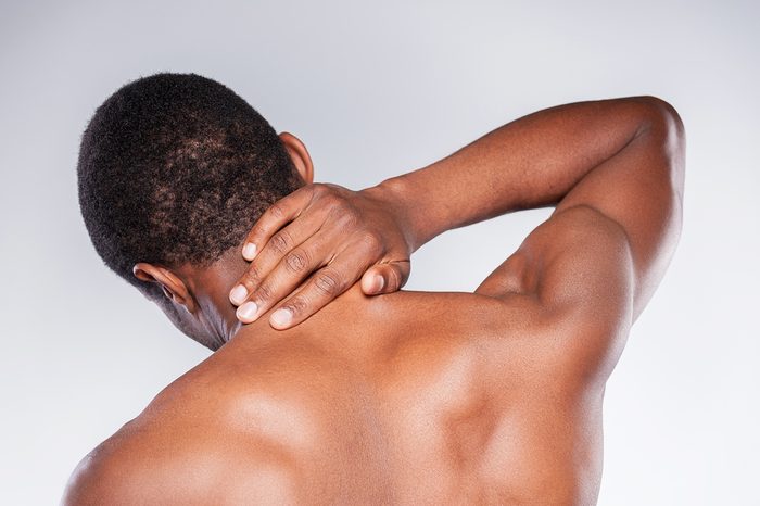 Young shirtless man touching his neck.
