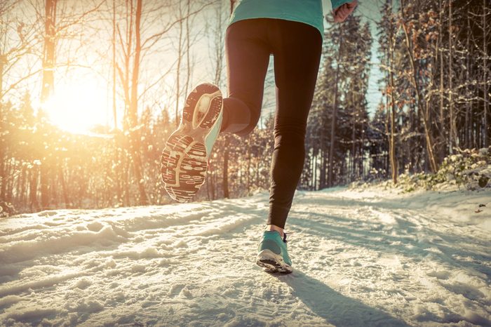 Woman Running at snowly winter under sunlight.