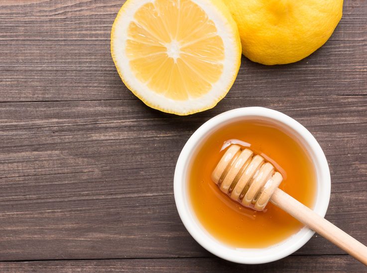 Bowl of sweet honey and lemons on wooden table.