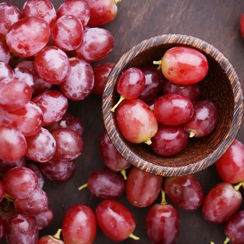 Red grapes on wooden table - vintage filter.