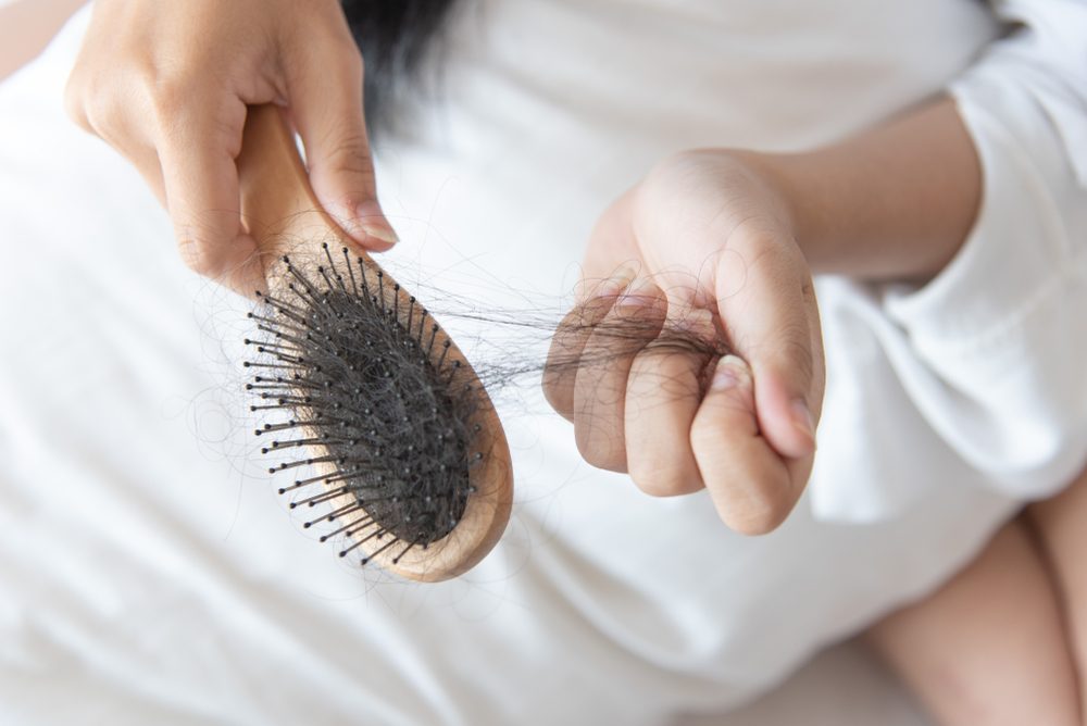 woman show her brush for presentation  hair loss problem and looking at her hair