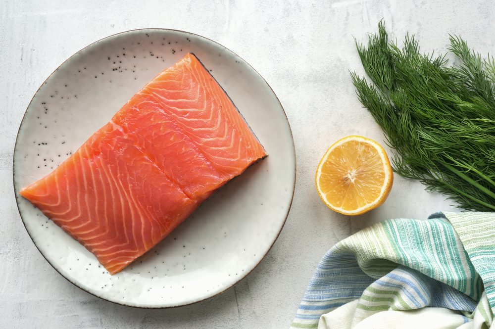 Fresh salmon steak, lemon, black peppercorn and dill on concrete table. Top view. Scandinavian ingredients for cooking. Overhead view. 