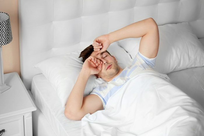 Sleepy young man rubbing his eyes in the morning.