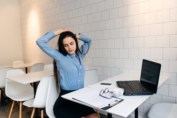 young brunette girl in a blue shirt is sitting in a cafe after work