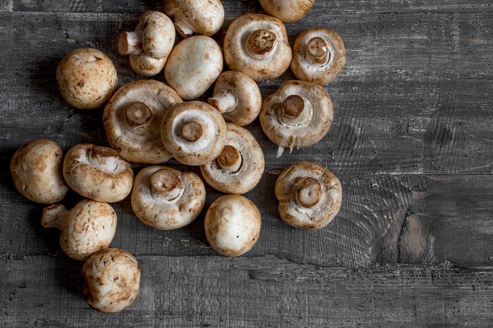 Flat lay mushrooms champignon on dark wood desk top view layout