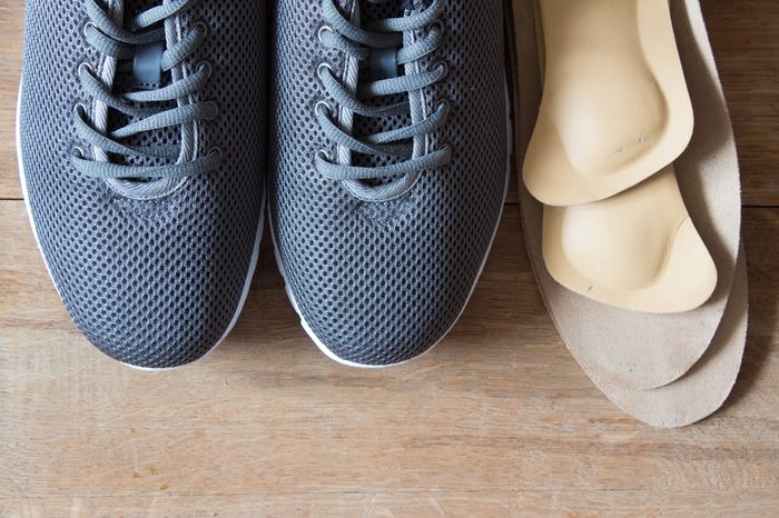 Gray sport shoes with orthopedic insoles. Wooden background.